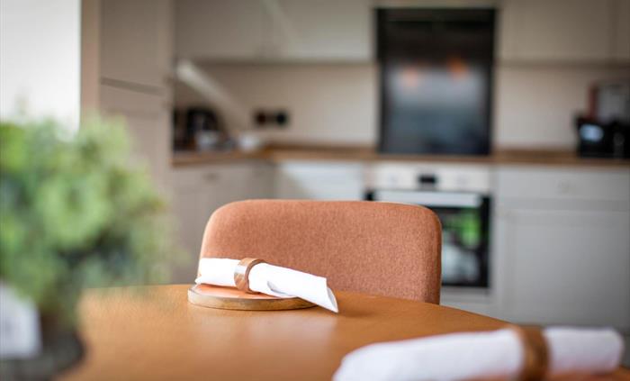 Dining table and chair with napkins and kitchen in background